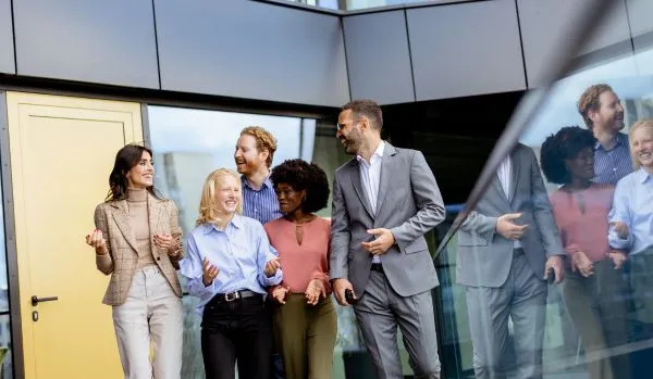 A diverse team of professionals is walking together, smiling and laughing.