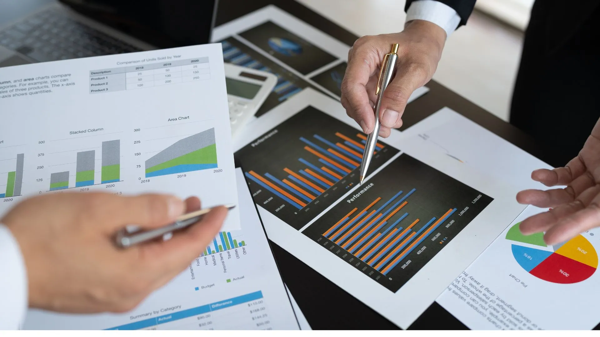 Close-up of two professionals reviewing printed financial charts with bar and area graphs. This scene highlights how learning the basics of business finance gives learners foundational skills to interpret and manage key financial data.