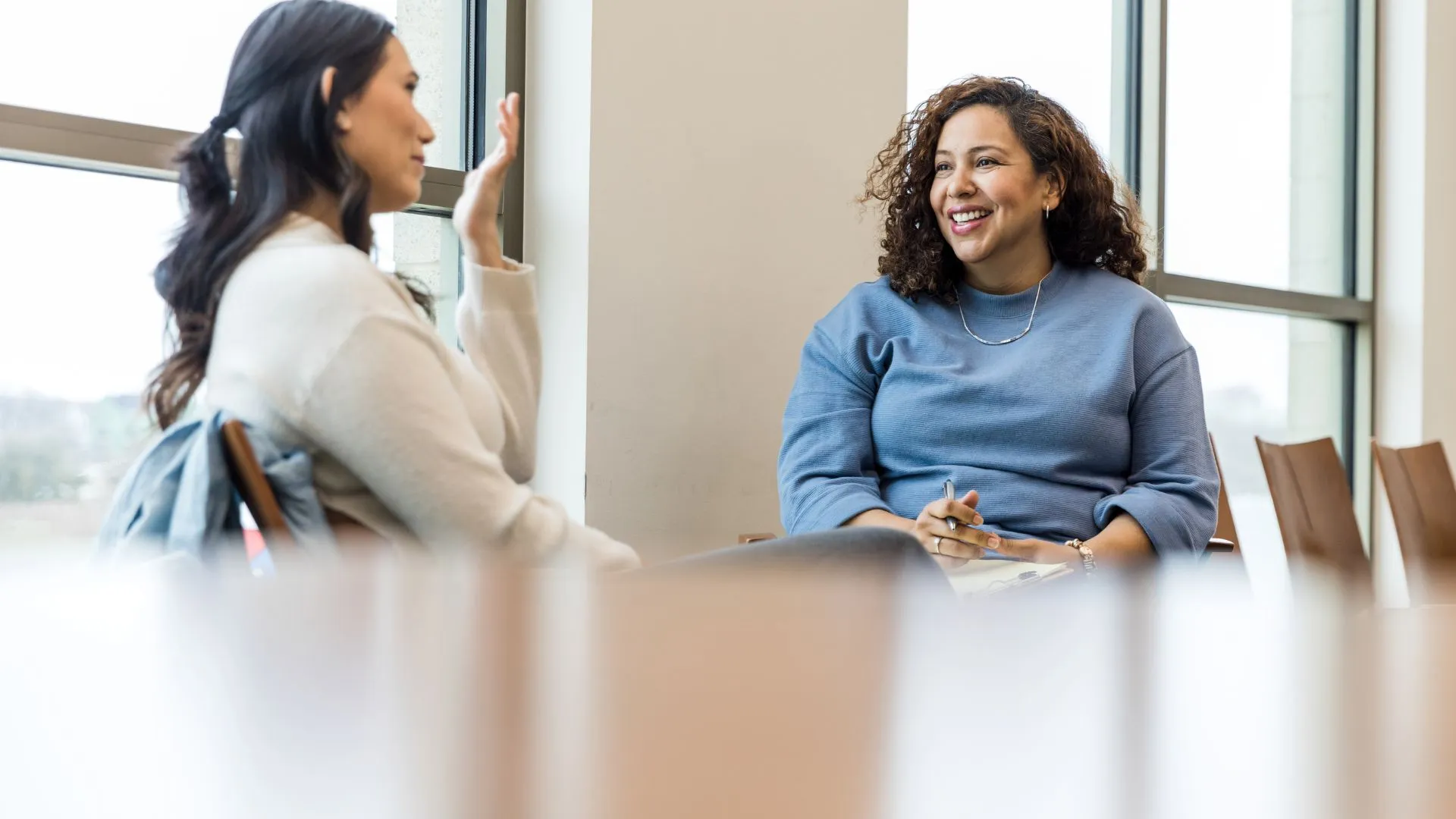 Two women are sitting in a conference room having a mid-year review conversation.