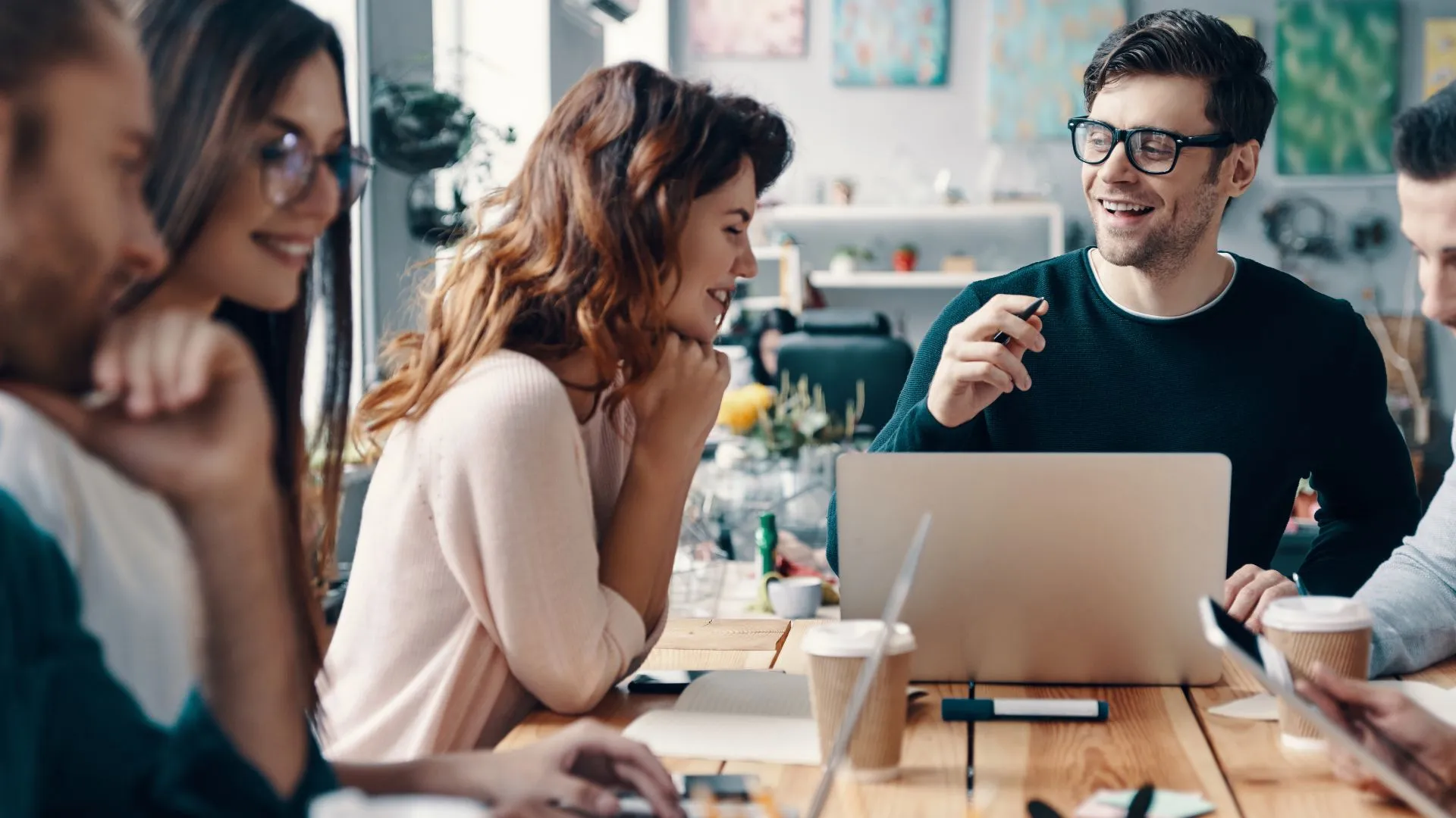 A group of colleagues are conversing and laughing around a conference table.