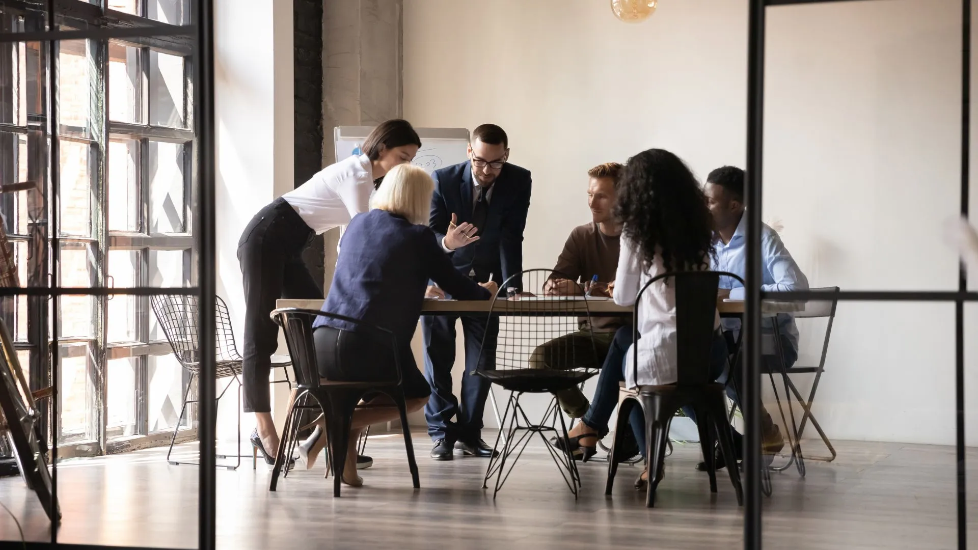 A diverse group of people are engaged in deep conversation around a table in an office space. 