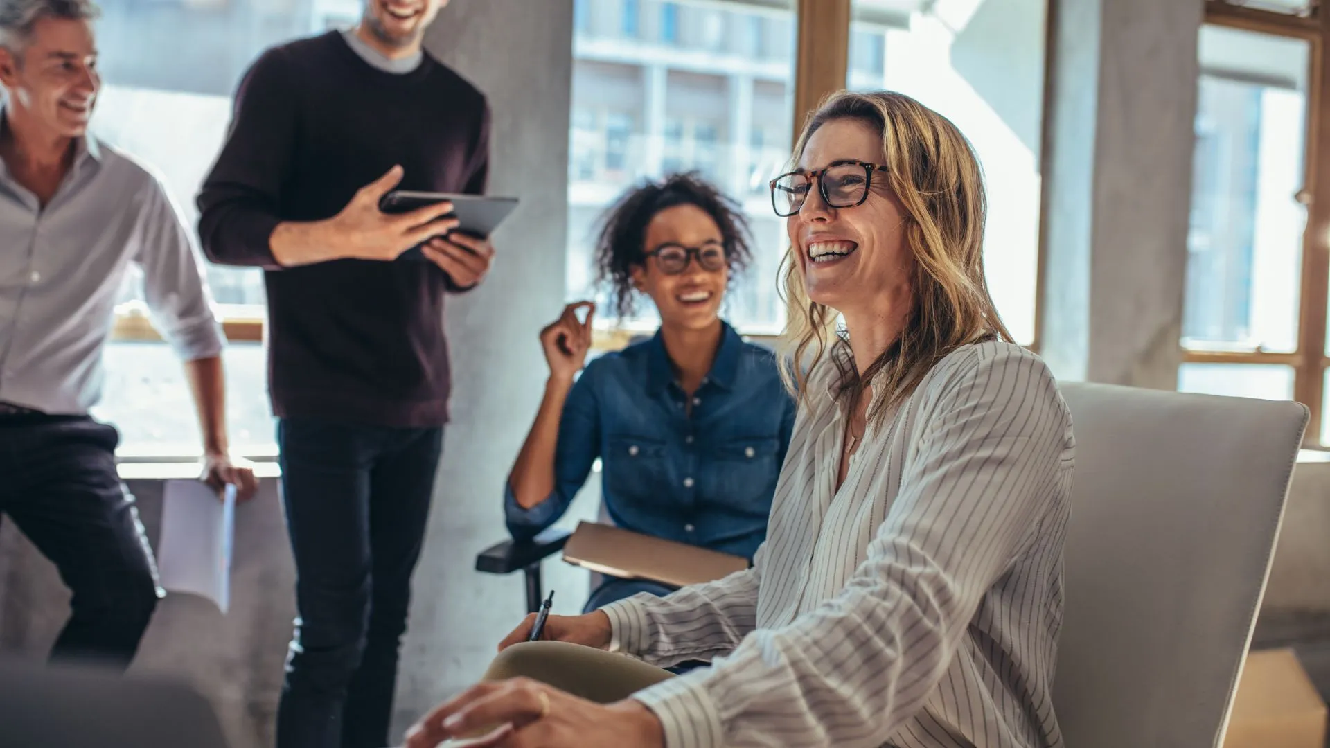 An engaged team is laughing and chatting in a common space.