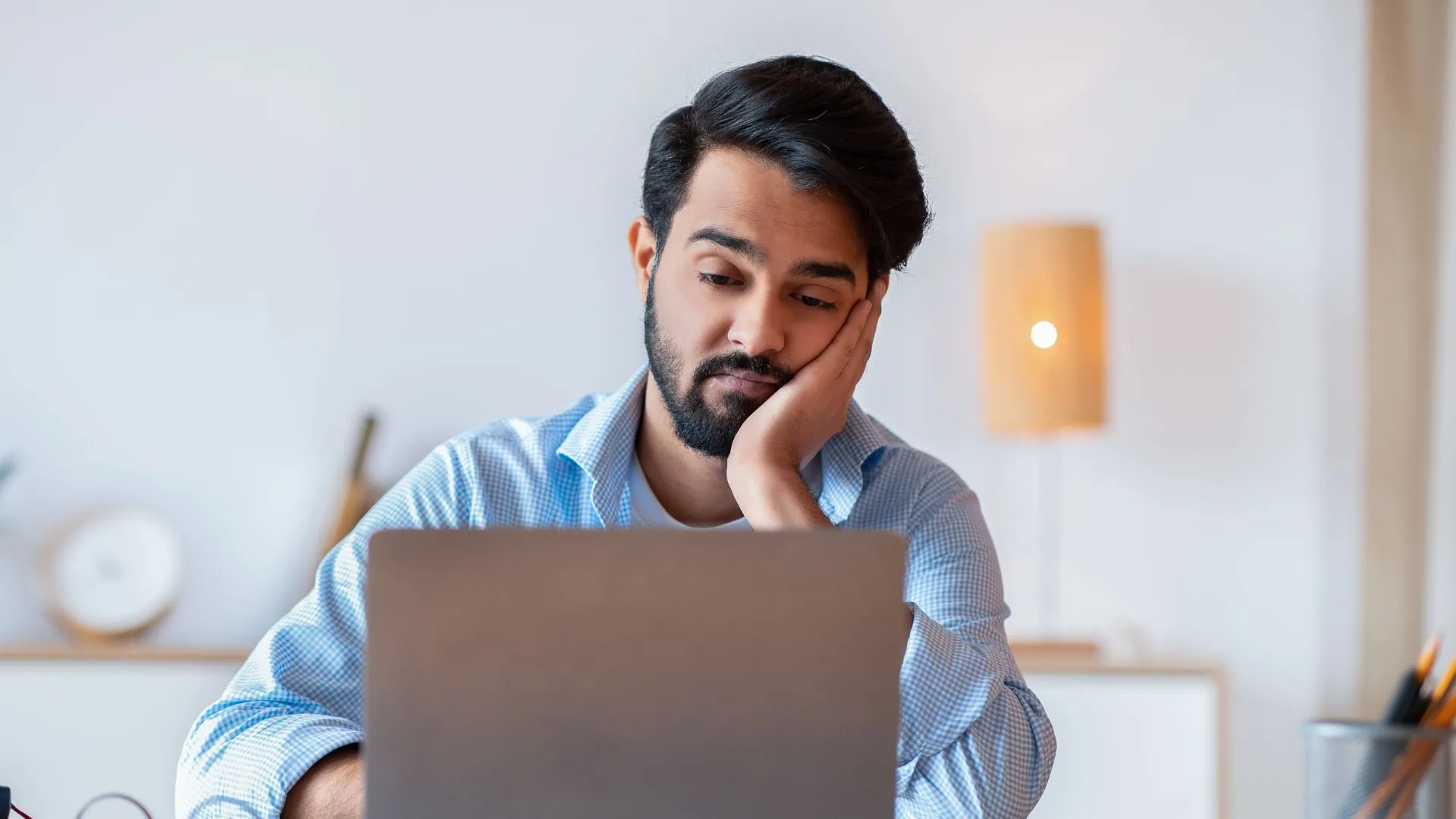 A person is watching a pre-recorded training video with a bored look on their face.