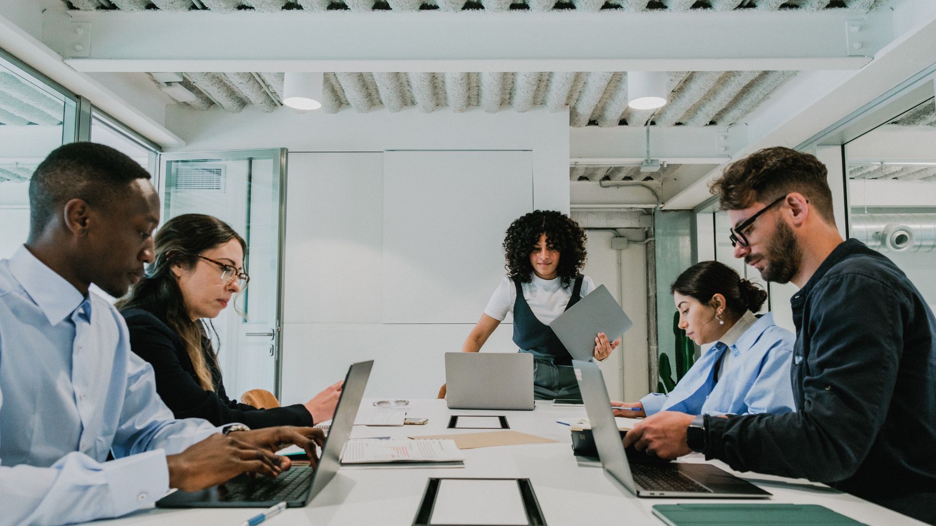 A team is quietly working around a conference table on their laptops.
