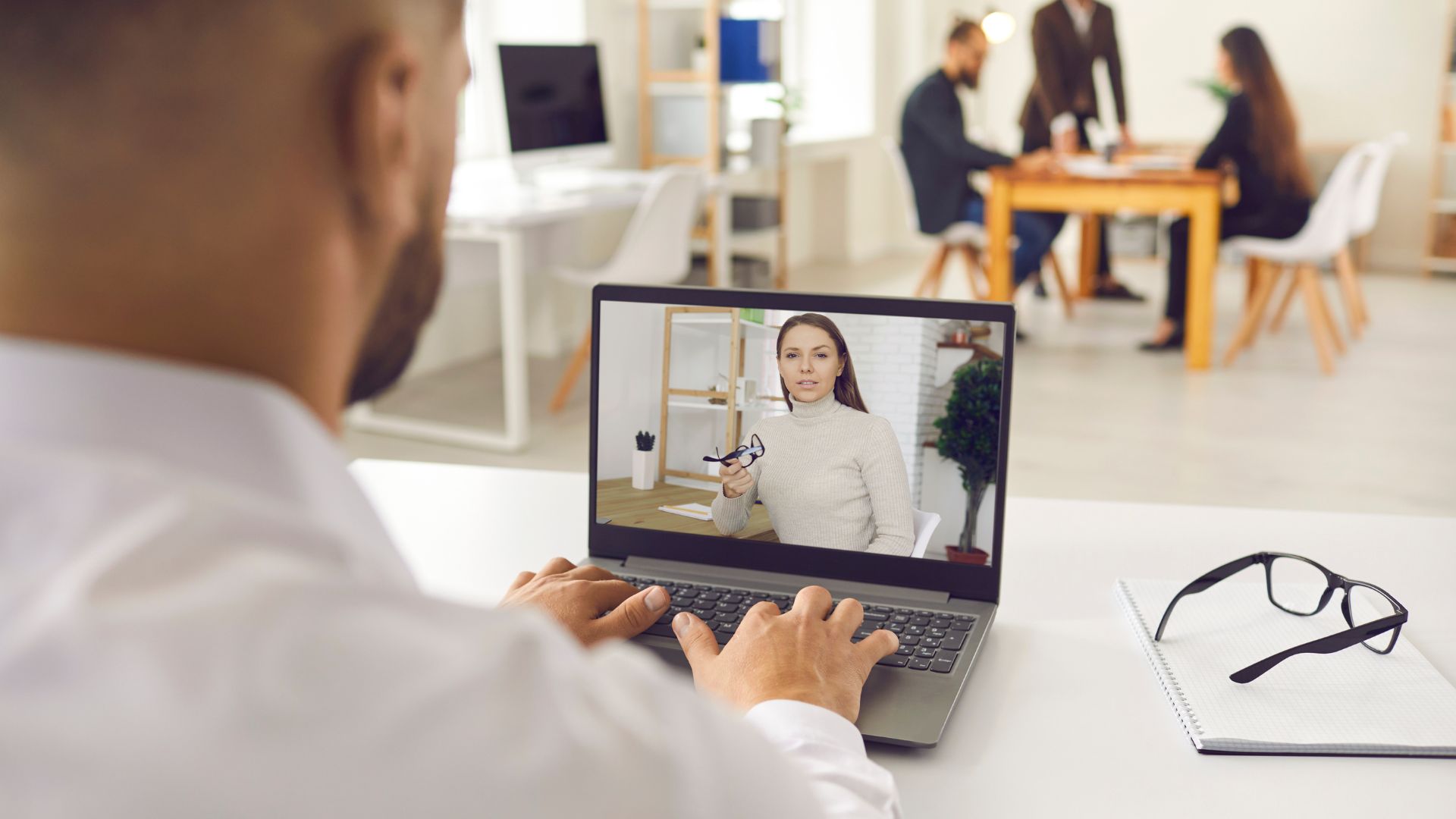An employee is being coached virtually by his manager, who appears on his laptop screen.