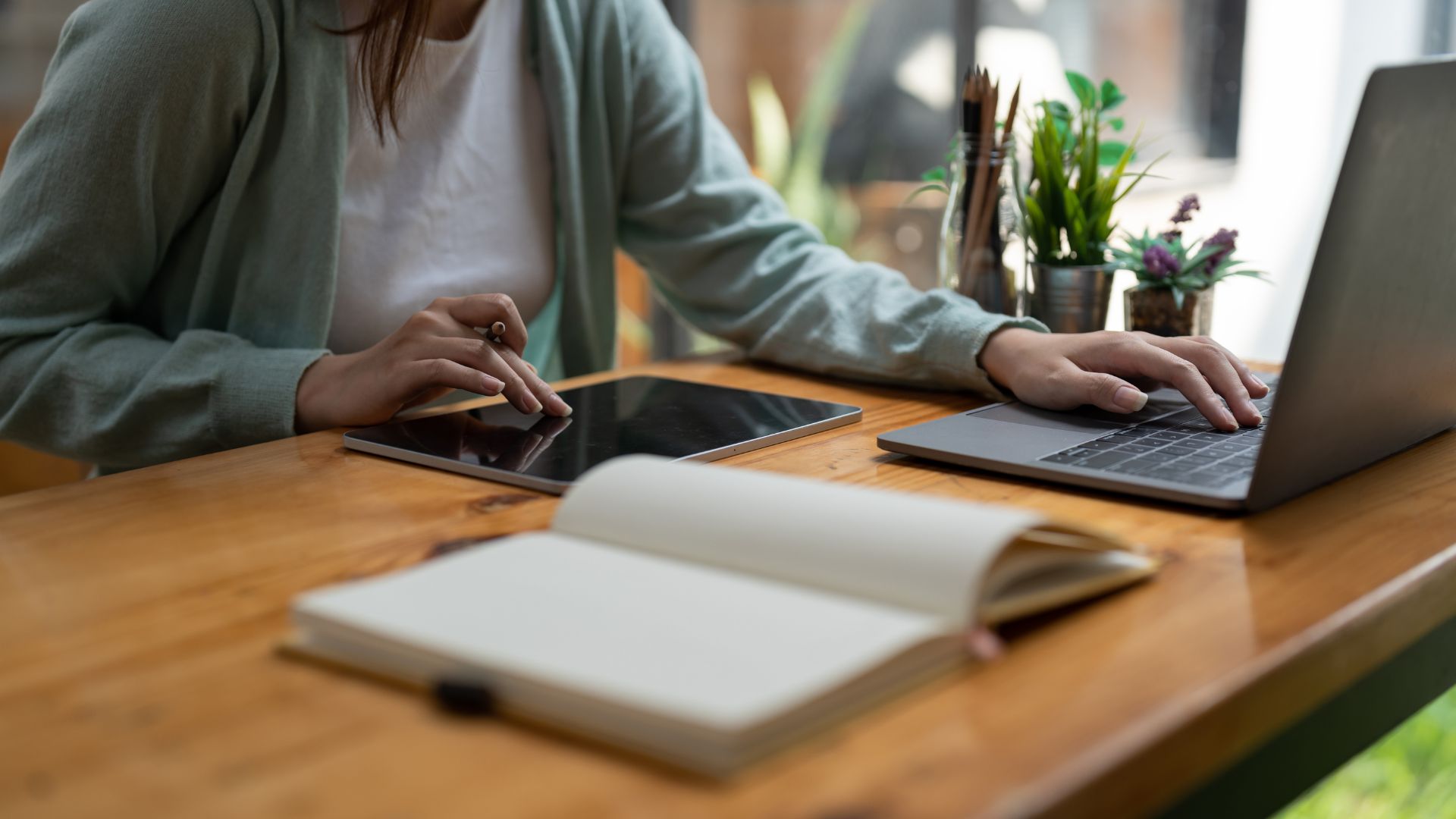 We're looking at someone's hands on their tablet and laptop at a table.