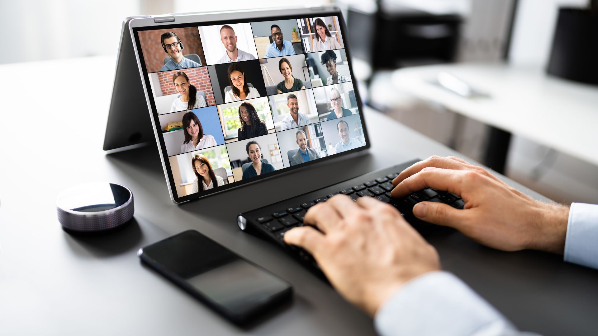 we're looking at someone's hands on their laptop keyboard. on the screen they're participating in a virtual meeting.