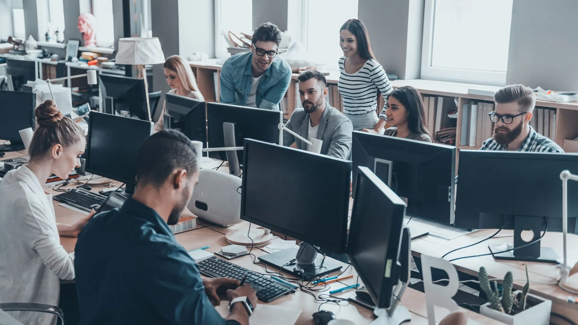A diverse team of people are working in an open concept office on an AI rollout plan.