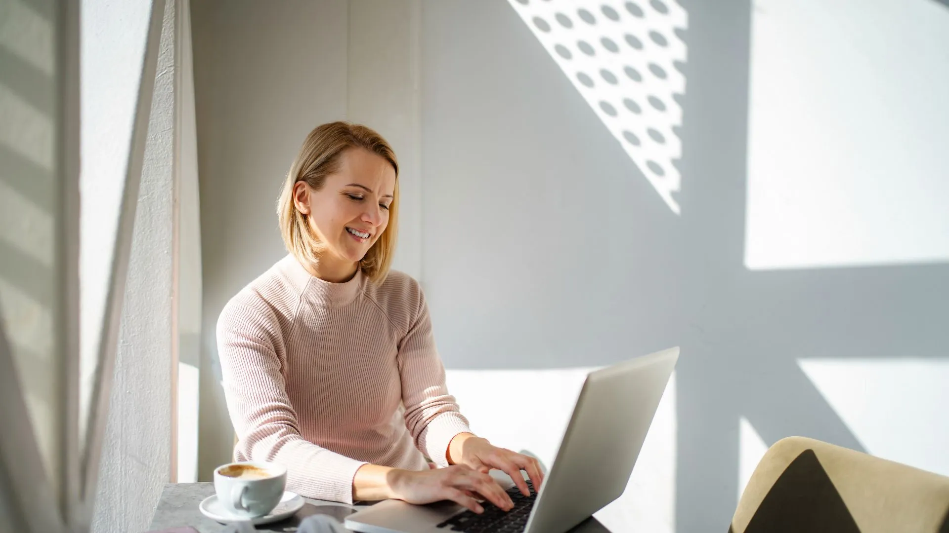 A woman is using AI on her laptop in a coffee shop.