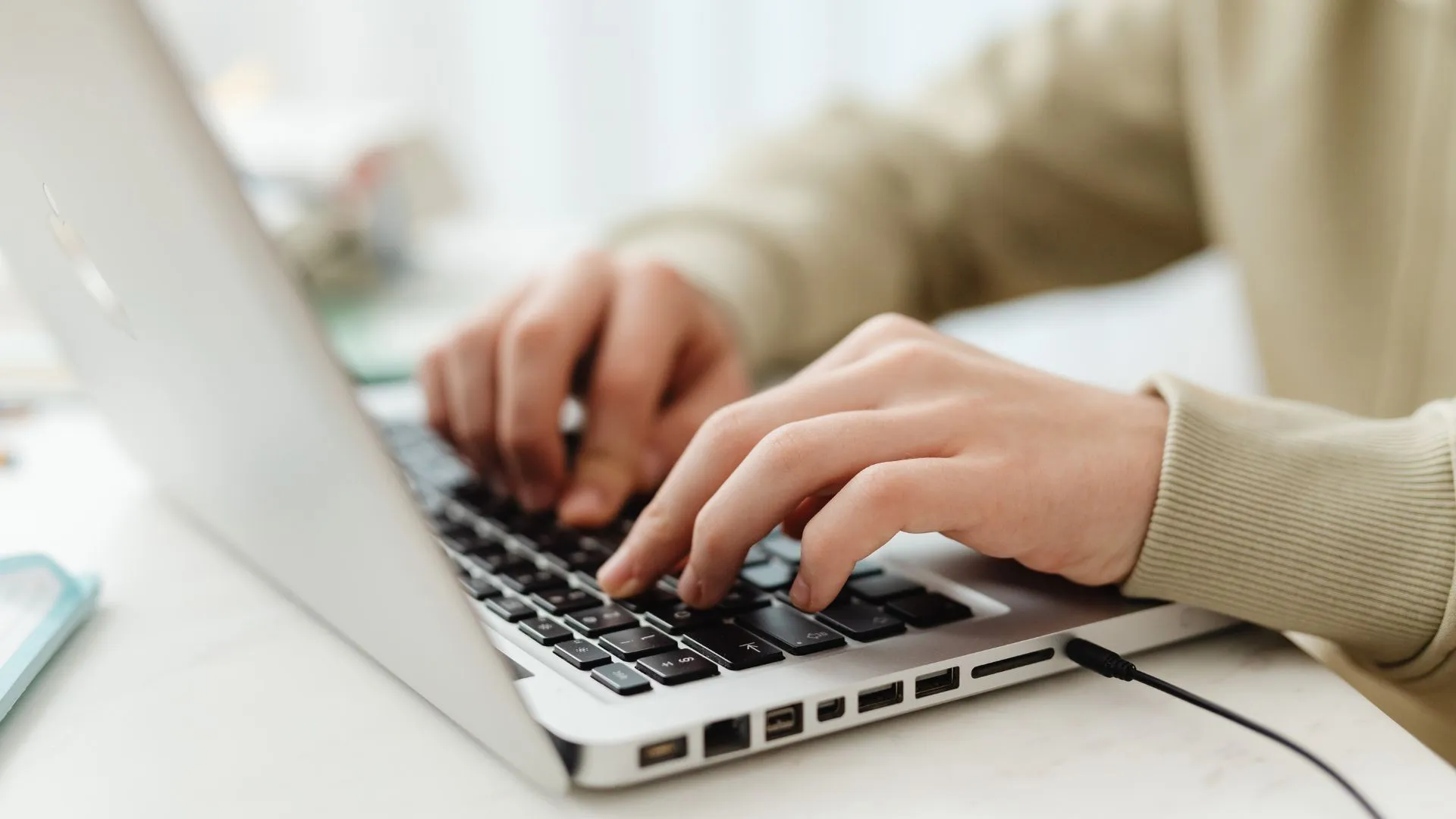 Close-up shot of hands typing on a laptop as the person evaluates different learning platforms. 