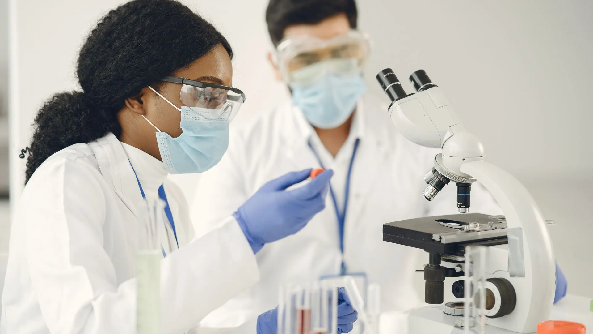 A man and woman are working with a microscope.