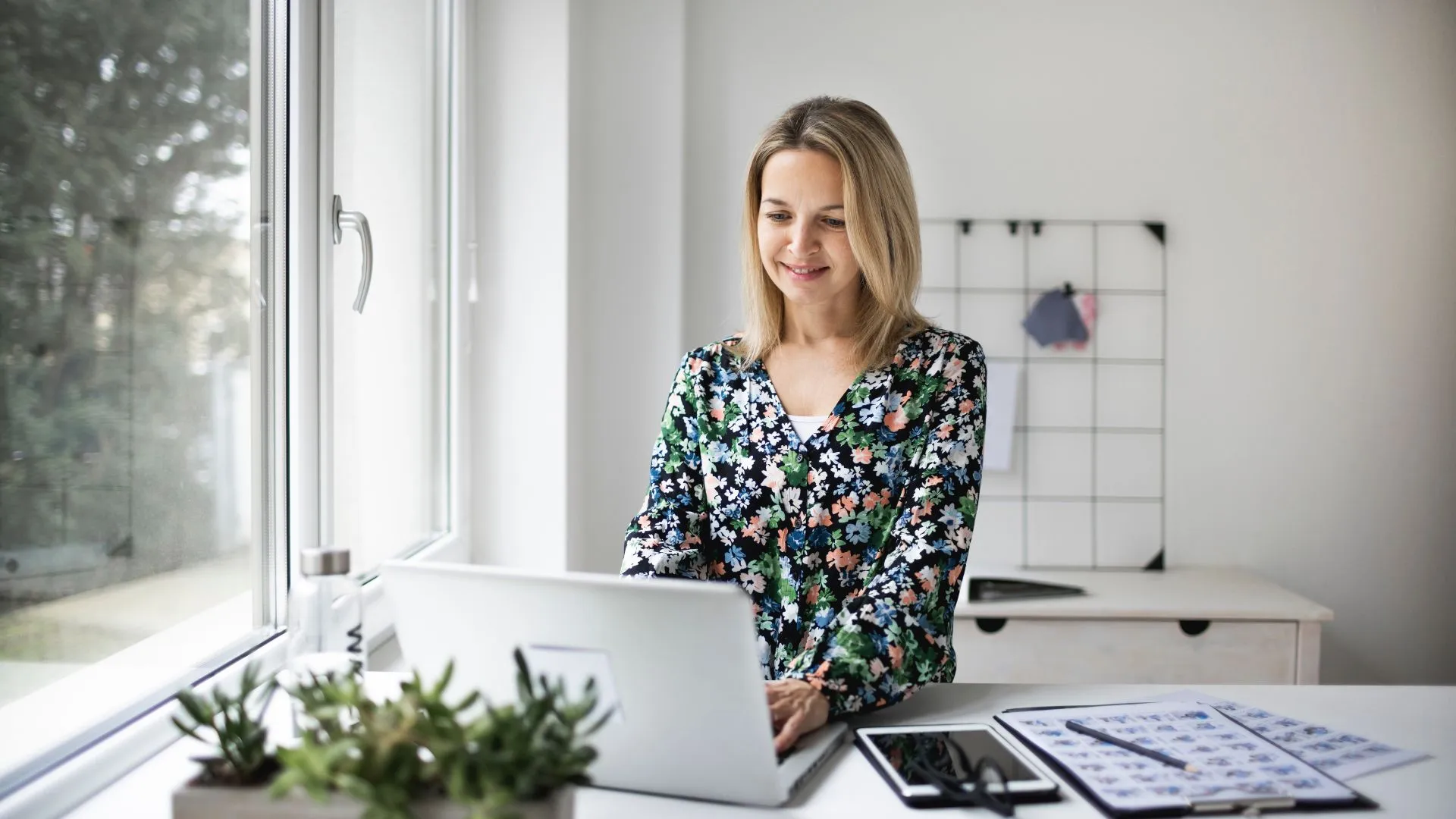 A woman is working on her laptop at a standing desk.
