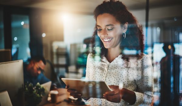A young woman is smiling down at a tablet she is using to watch an AI training.
