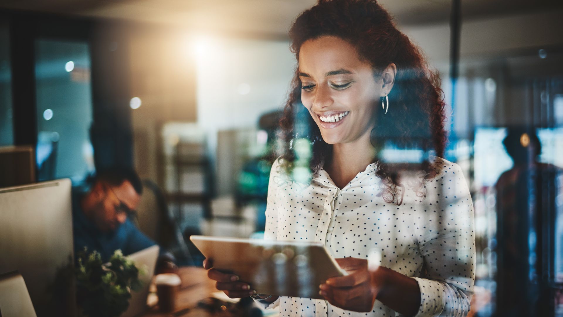 A young woman is smiling down at a tablet she is using to watch an AI training.