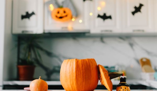 A Jack-o-lantern sits on the counter of an office break room that is decorated for Halloween.