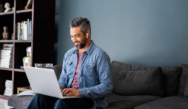 A man is working from home, reading on his laptop.