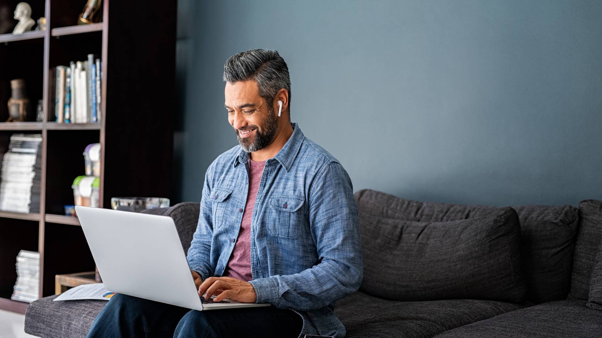 A man is working from home, reading on his laptop.
