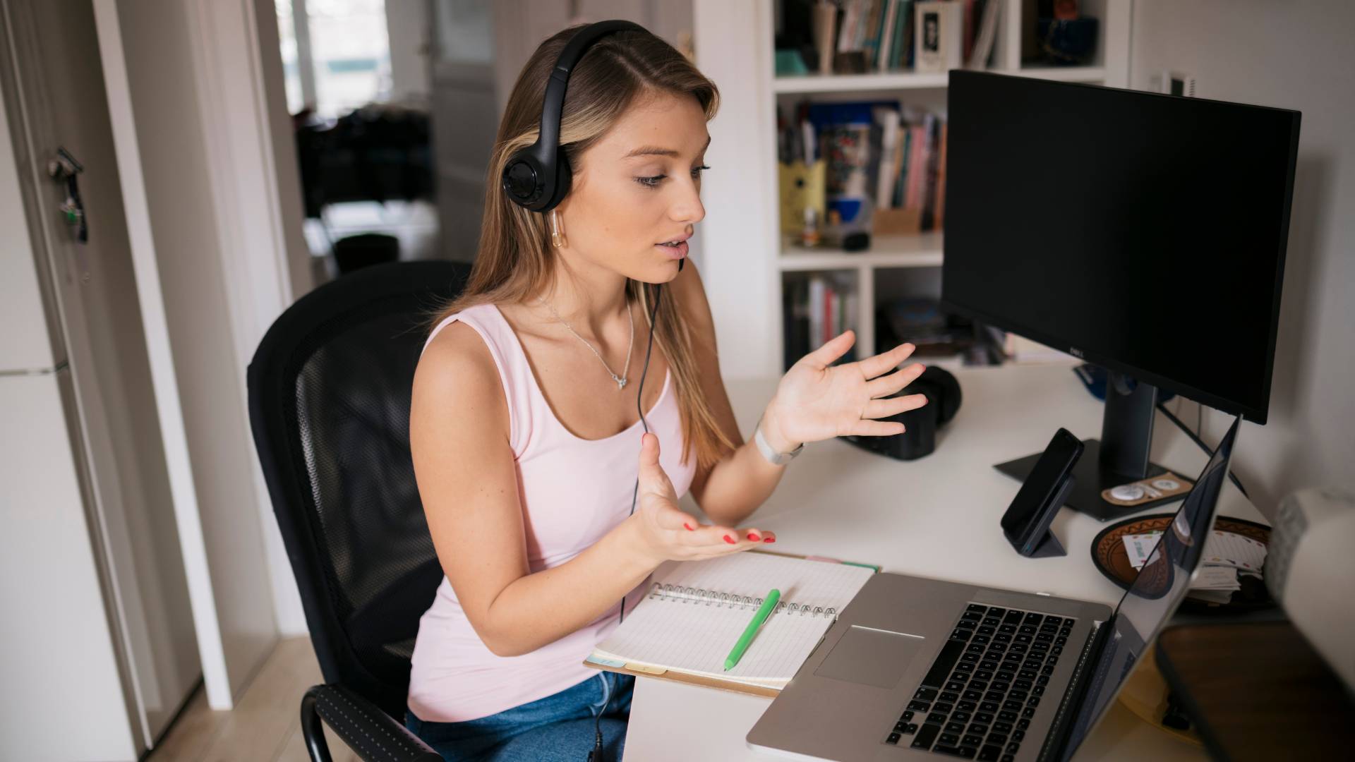 A young woman is talking to someone virtually on her laptop.