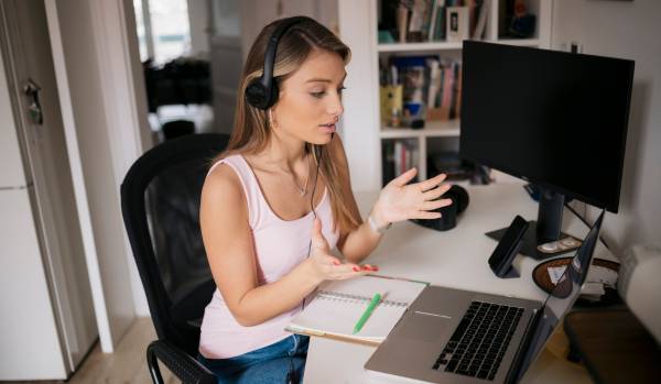 A young woman is talking to someone virtually on her laptop.