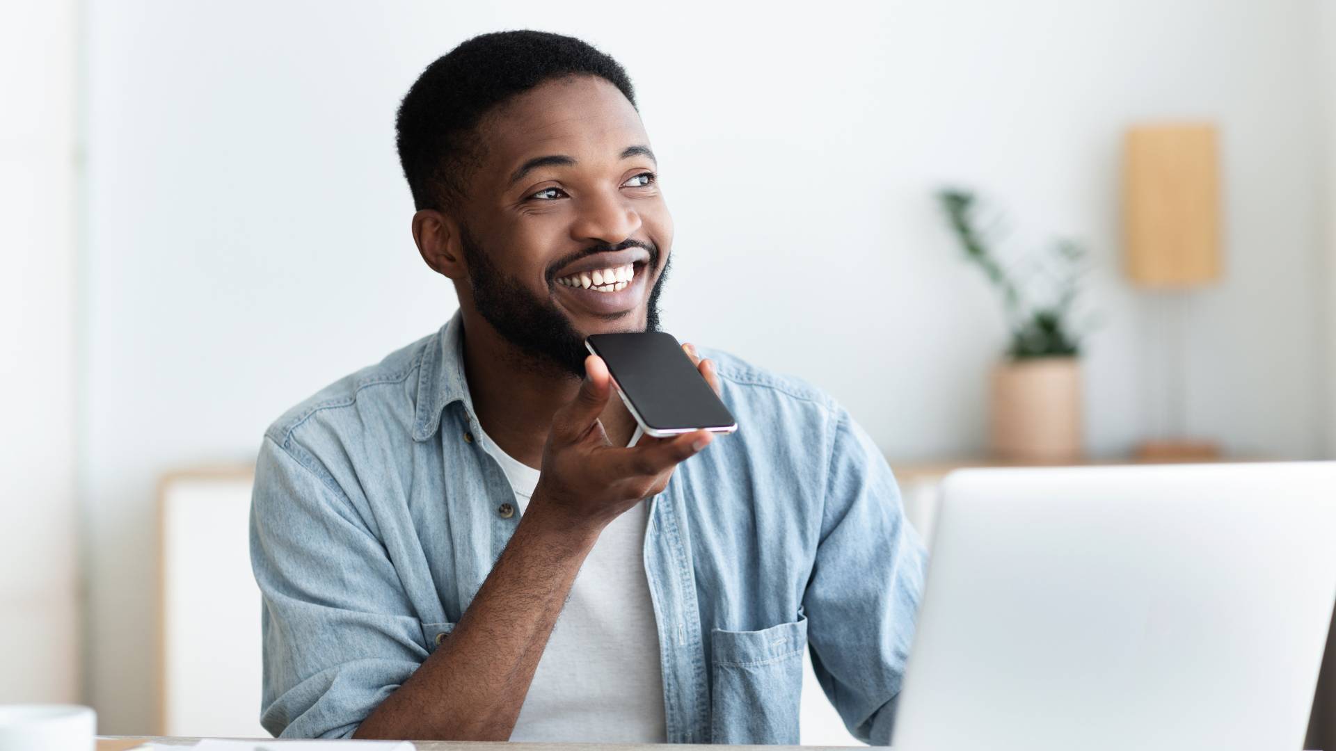 A young man is holding his phone up to his face as he uses its AI tool.