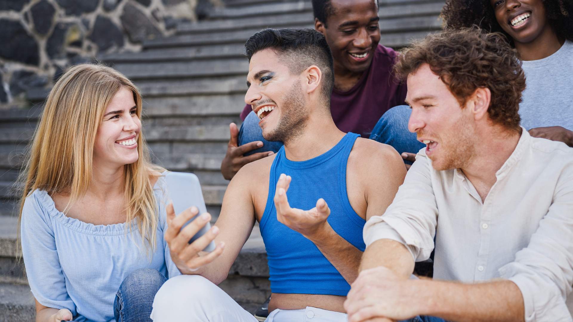 Diverse group of people sitting on stairs outdoors, laughing and smiling