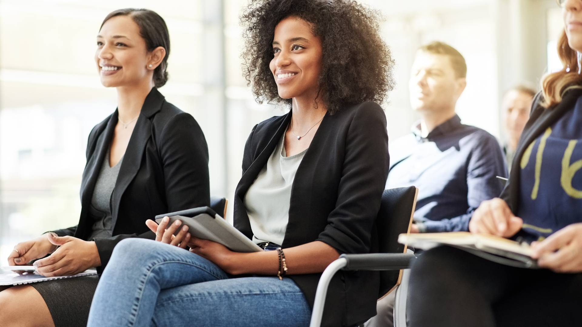 A group of professionals are sitting in a classroom-style training environment.