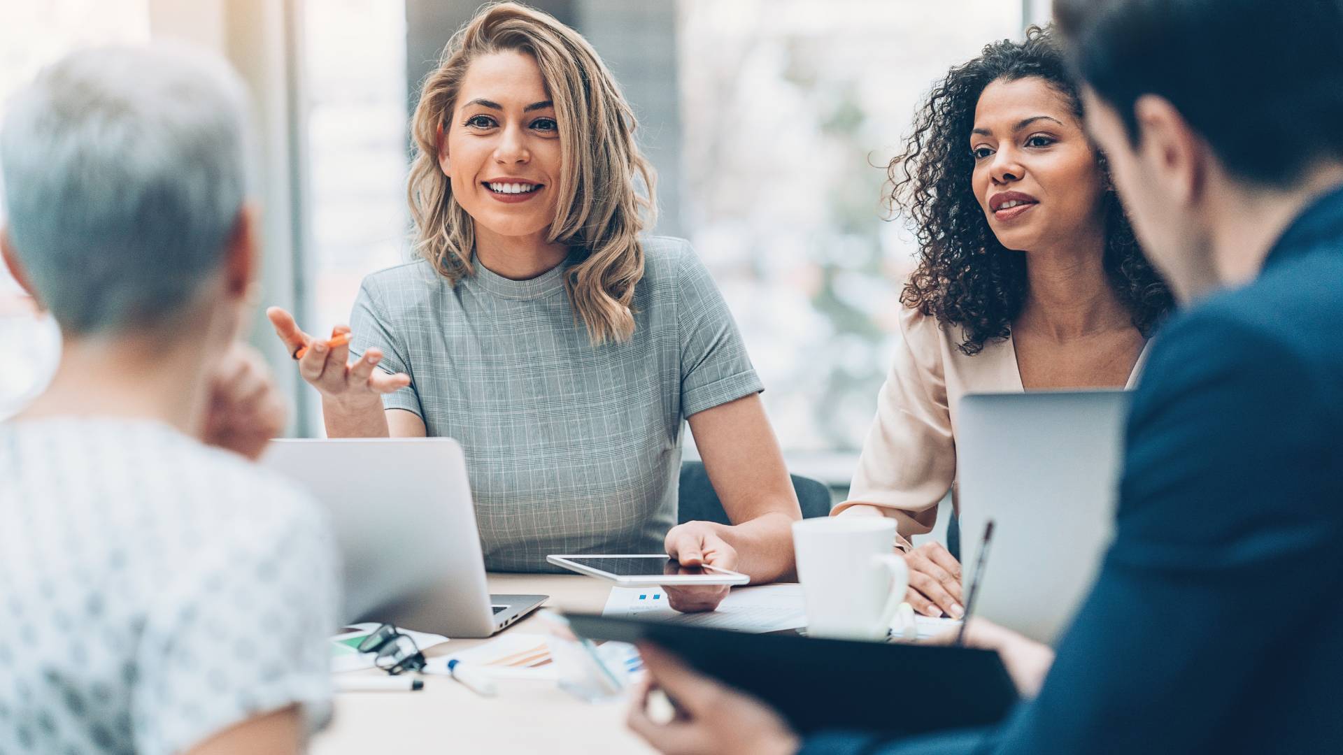 There are four people sitting at a table having a discussion in an office setting.