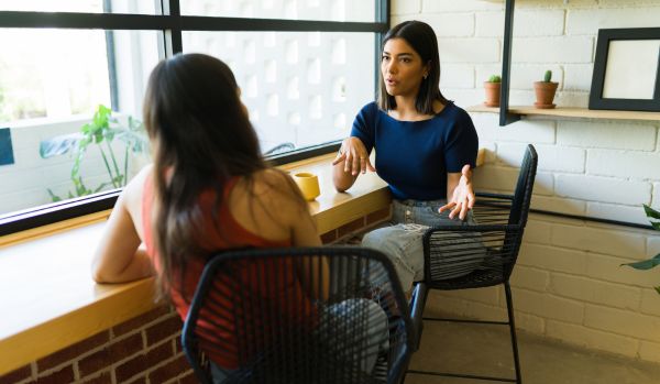 We're looking at two women sitting next to a counter having a deep conversation.