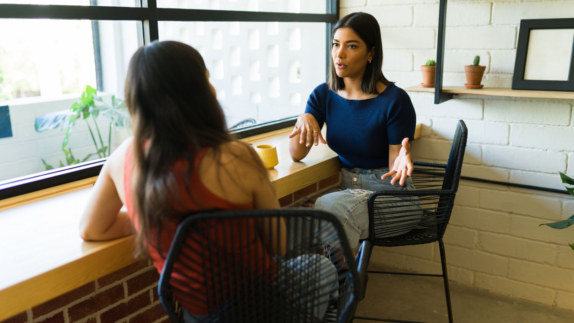 We're looking at two women sitting next to a counter having a deep conversation.