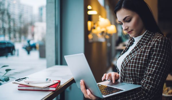 A young woman is using her laptop at a coffee shop.