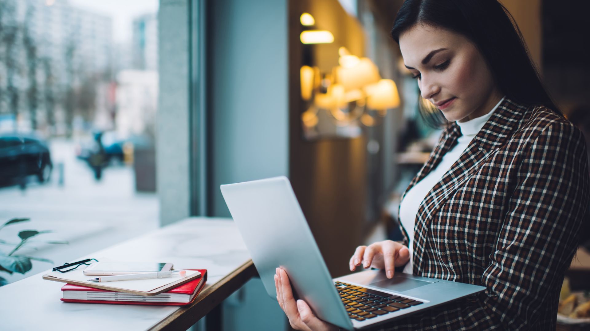 A young woman is using her laptop at a coffee shop.