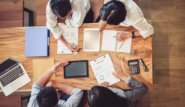 We're looking down at a group of people reviewing budgets at a conference table.