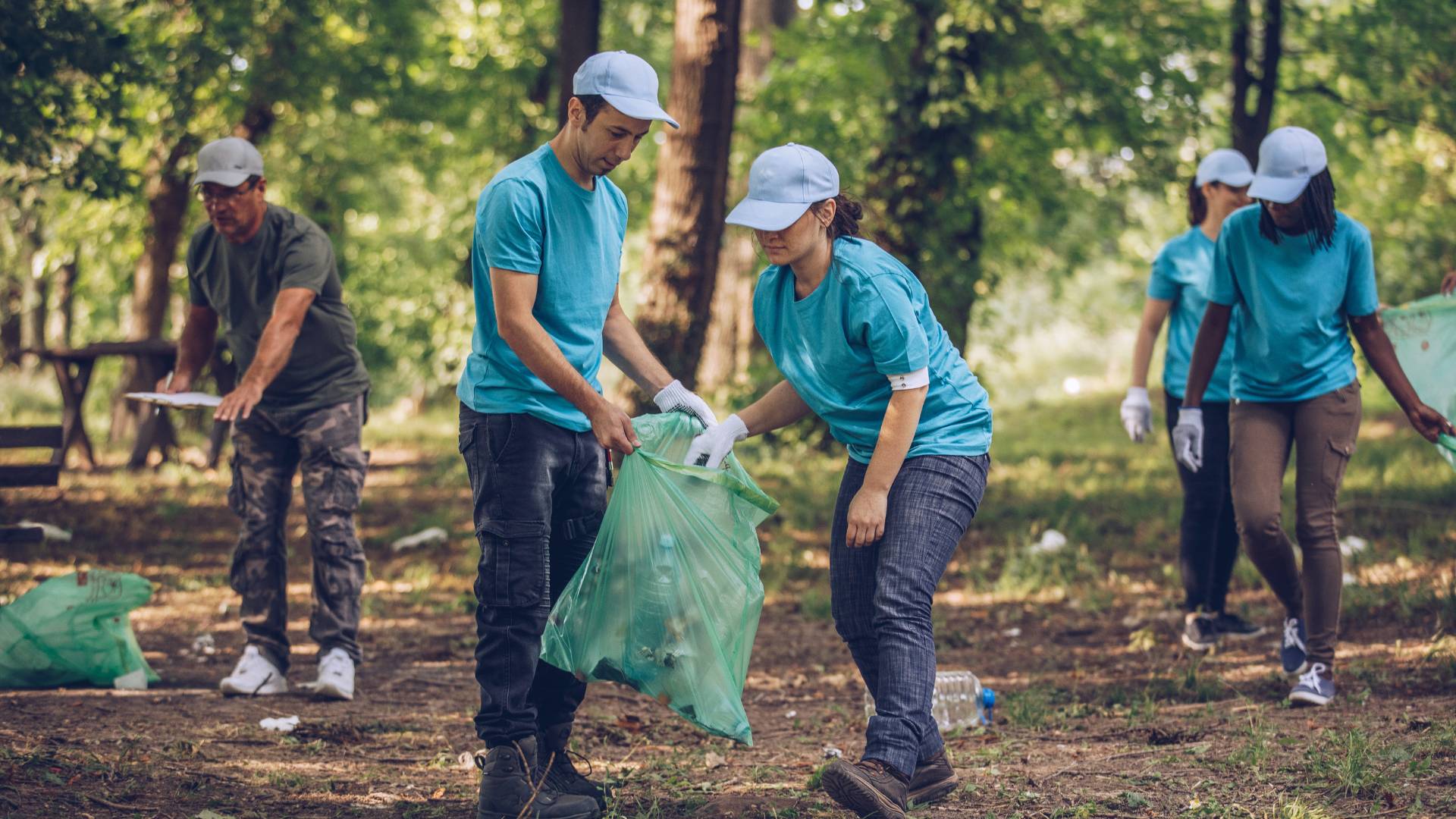 A team of employees works together to clean up litter in a wooded area.
