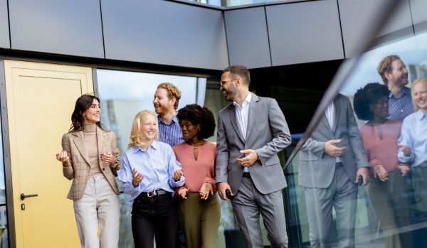 A diverse team of professionals is walking together, smiling and laughing.