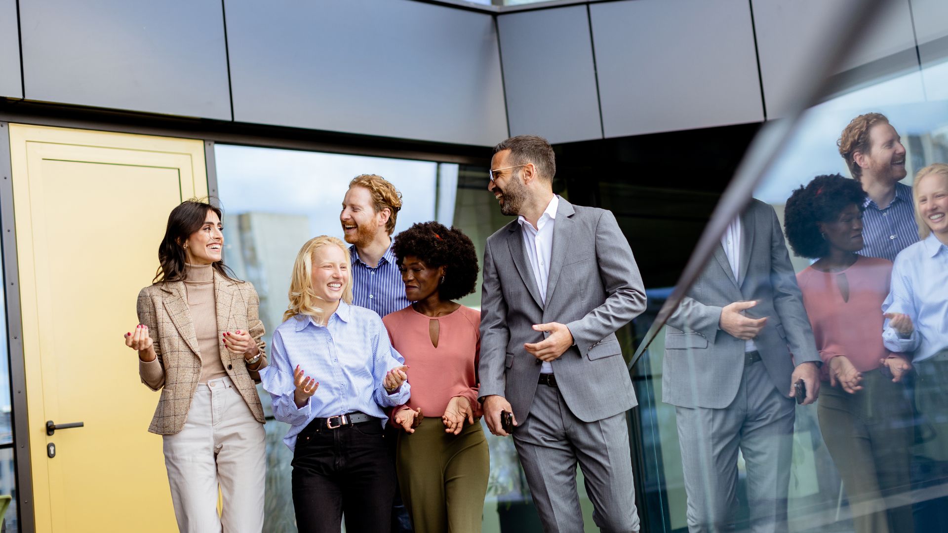 A diverse team of professionals is walking together, smiling and laughing.