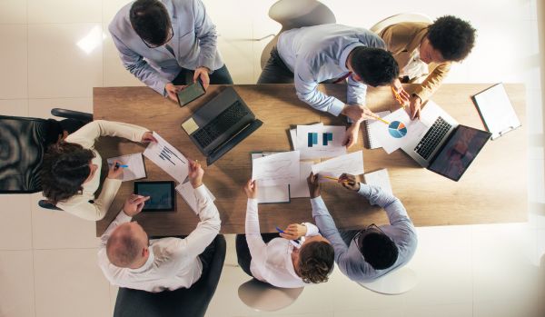 We're looking down from overhead at a team of people reviewing data together around a conference table.