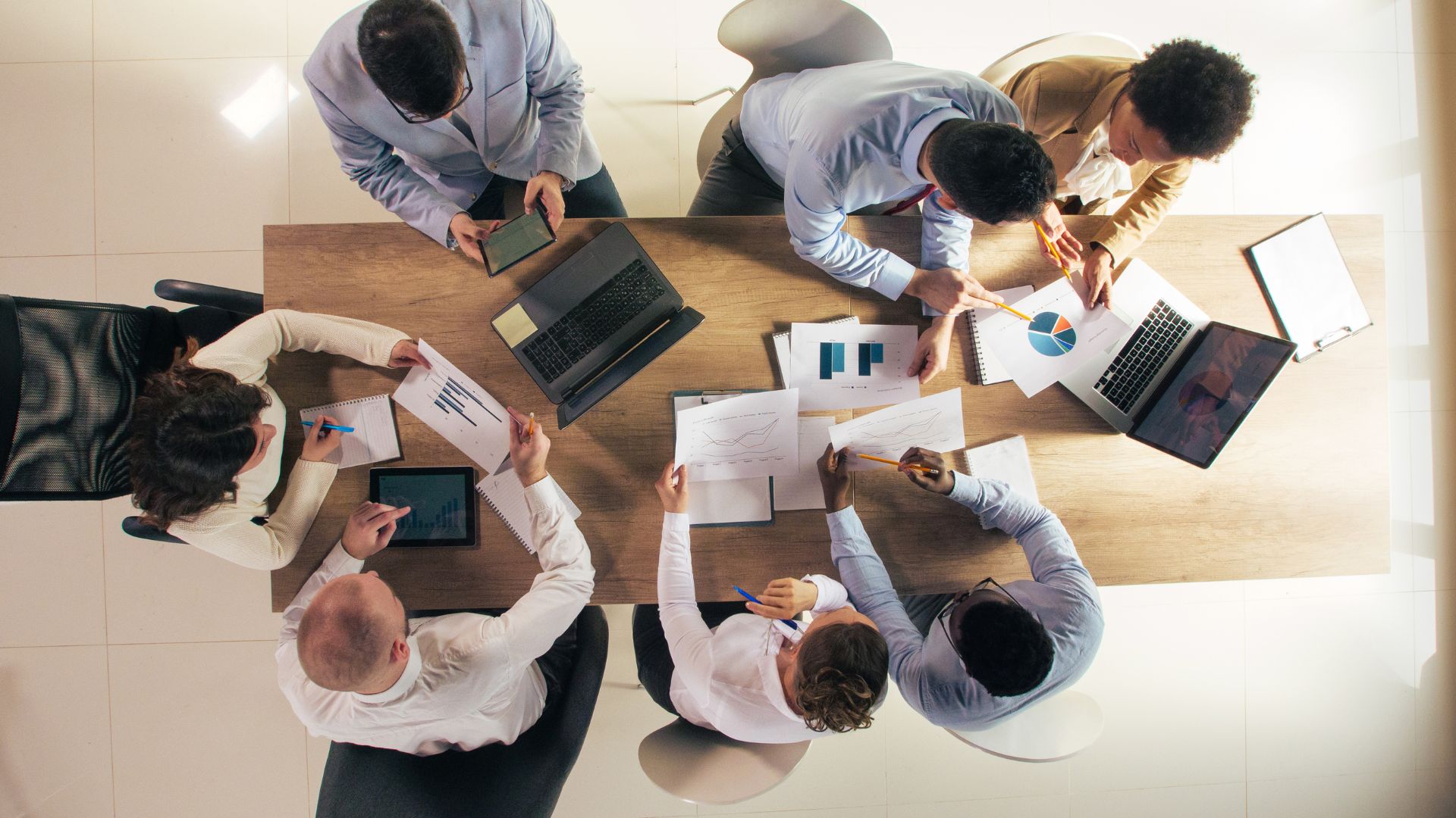 We're looking down from overhead at a team of people reviewing data together around a conference table.