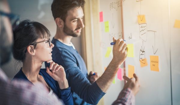 A team of people are working on a white board to make a decision