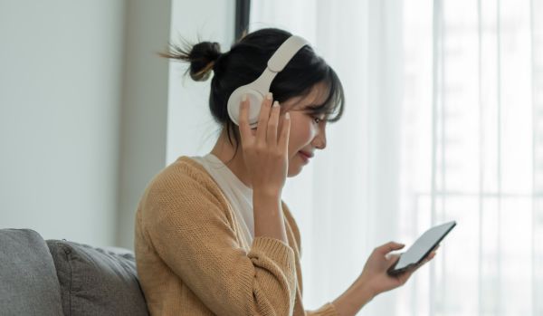 A person is listening to call on her cell phone from her bluetooth headphones.