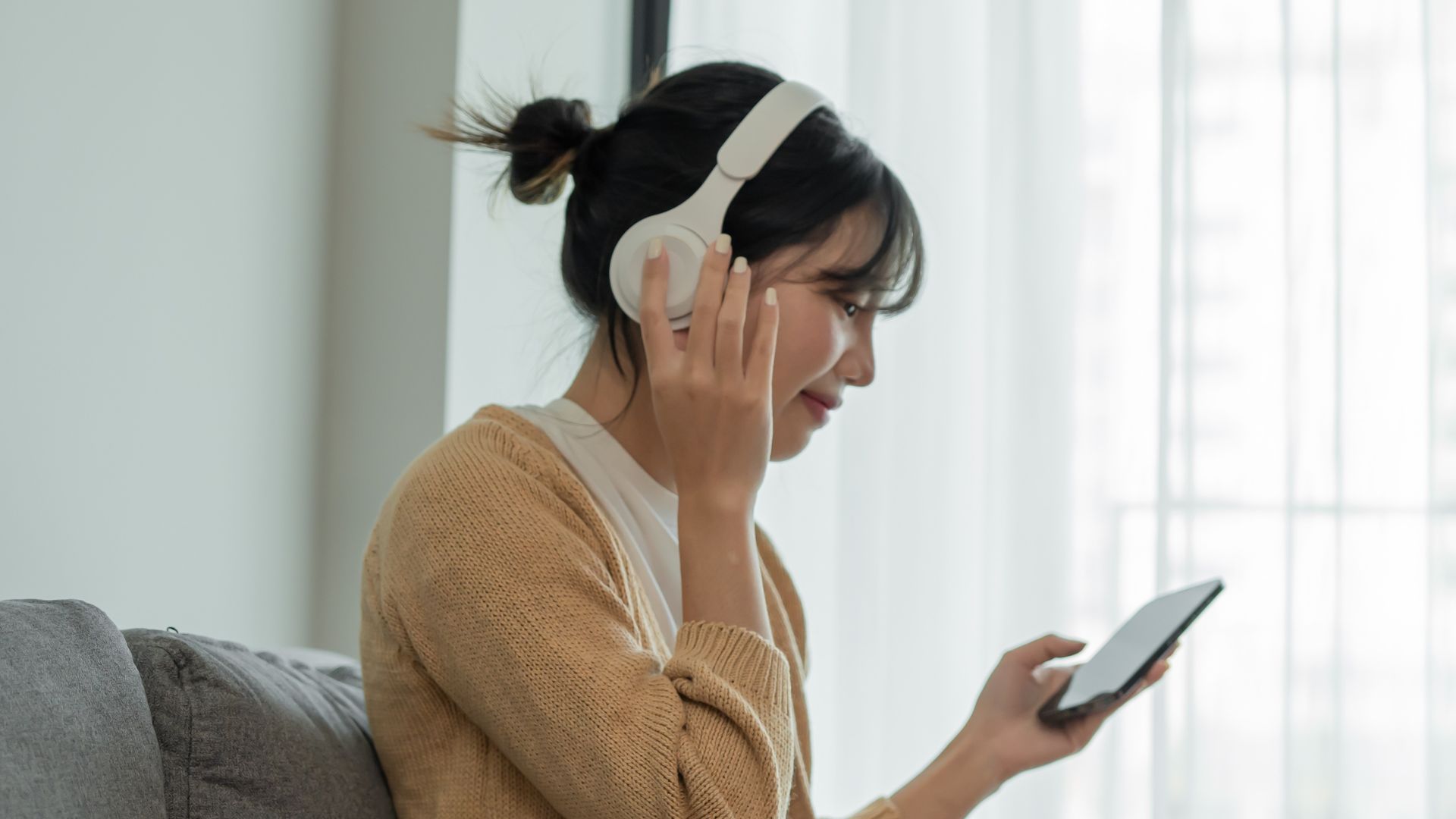 A person is listening to call on her cell phone from her bluetooth headphones.