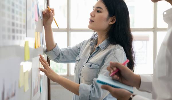 A young woman is working on a whiteboard.