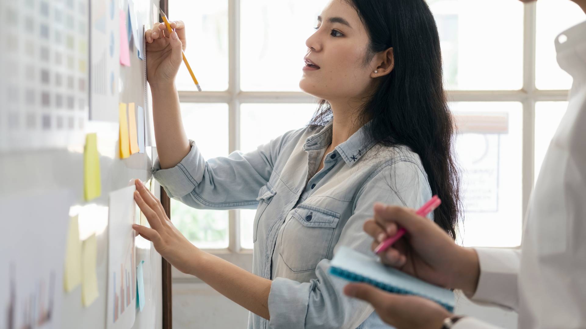 A young woman is working on a whiteboard.