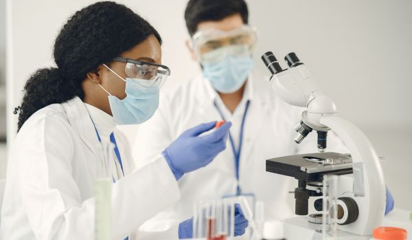 A man and woman are working with a microscope.