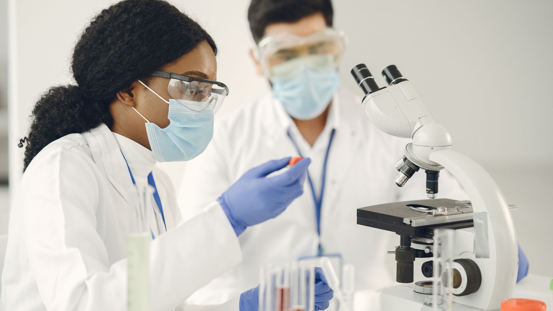 A man and woman are working with a microscope.