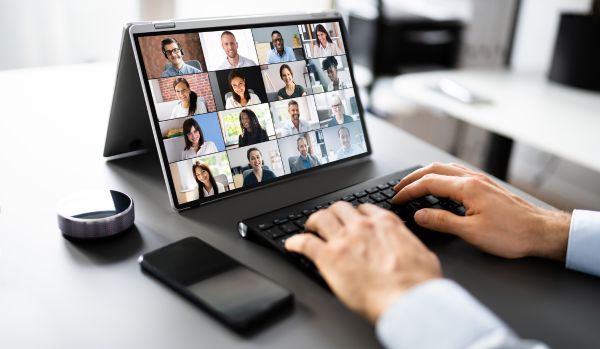 we're looking at someone's hands on their laptop keyboard. on the screen they're participating in a virtual meeting.