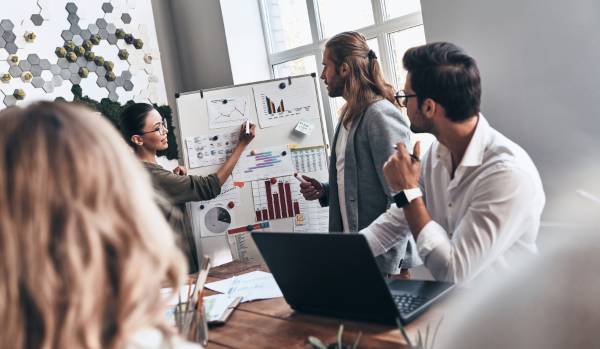 A team is working together on a project in a conference room on a flipchart.