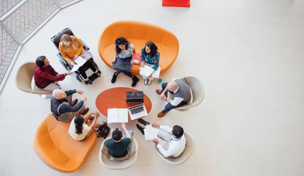 We are looking down from overhead at a diverse group of employees having a discussion in a sitting area.