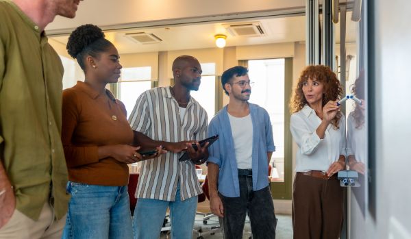 A diverse team of people in a casual office are all working together to solve a problem.