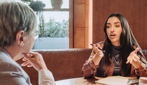 A two-person HR team is planning at a table in a common space.