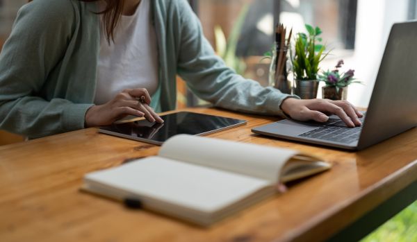 We're looking at someone's hands on their tablet and laptop at a table.